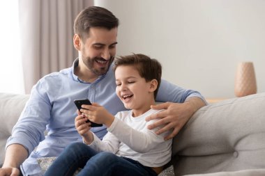 Gülen baba ve oğul akıllı telefon kullanıyor internette eğleniyor.