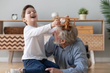 Küçük torun ve büyükbaba helikopterle tahta oyuncakla oynuyorlar.