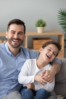 Mutlu baba, oğlunu kucaklıyor ve kanepeye oturuyor.