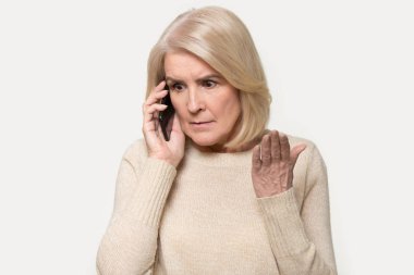 Sinirli yaşlı bir kadının akıllı telefondan tartışırken fotoğrafı.