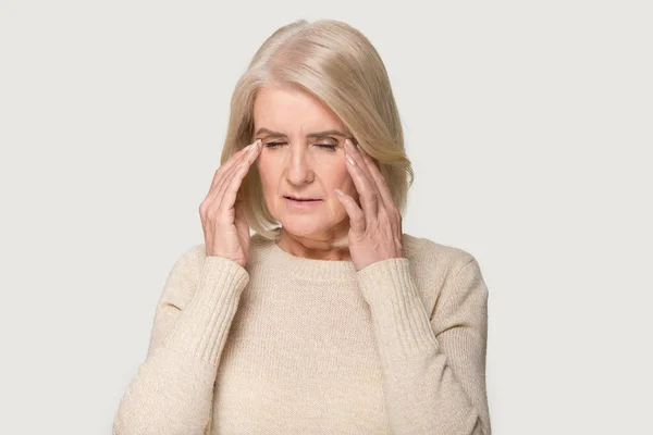 Korkunç baş ağrısı çeken yaşlı bir kadının gözleri kapalı fotoğrafı. — Stok fotoğraf