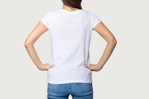 Millennial female wearing white t-shirt standing turning back to camera — ストック写真