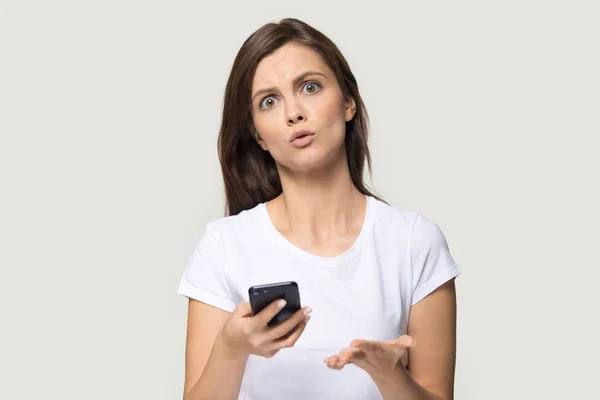 Headshot of confused woman holding phone with unhappy face — Stock Photo, Image