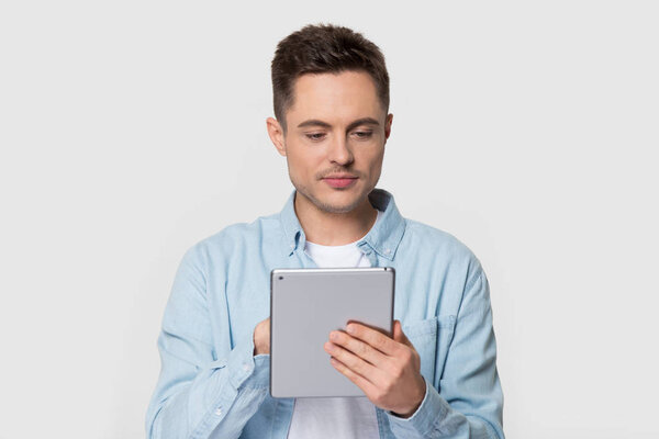 Handsome man standing scrolling and typing on electronic tablet device