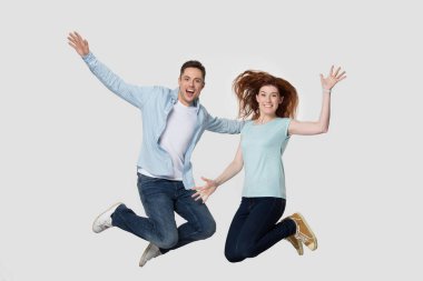 Gri stüdyo arka planında enerjik arkadaşlar birlikte yükseğe zıplıyorlar.