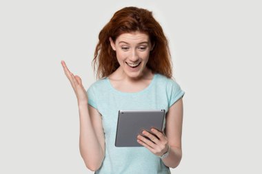 Tablet ekranına bakan heyecanlı kızıl saçlı kadın..