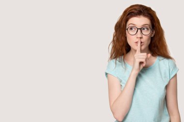 Genç kızıl saçlı kadın sessiz jest yapıyor..