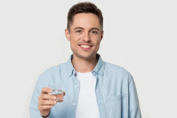 Smiling happy healthy young man holding glass of water. — Stock Photo, Image