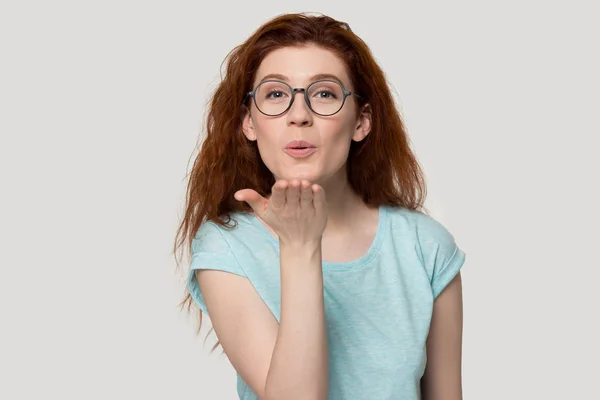 Millennial donna dai capelli rossi in occhiali da vista che invia baci aerei . — Foto Stock