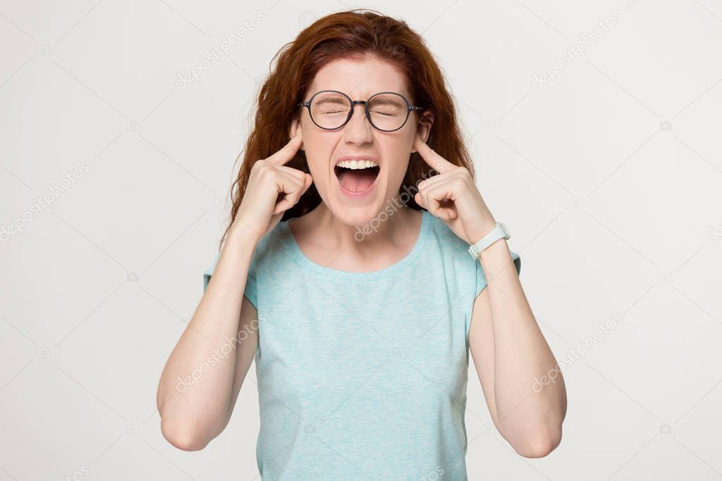 Angry woman sticking plug fingers in ears.