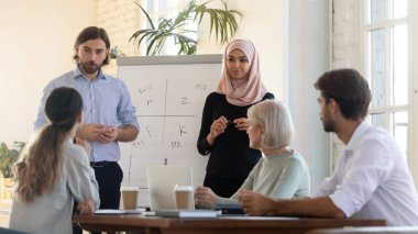 Çevirme grafiği yakınında proje fikirlerini sunan odaklanmış karışık ırk konuşmacıları.