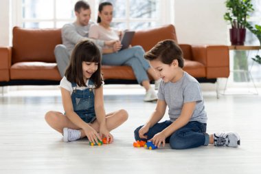 Mutlu erkek ve kız kardeşler yerde oturup oyuncaklarla oynuyorlar..