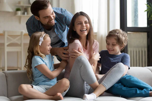 Mann mit kleinen Kindern kitzelt lachende Frau — Stockfoto