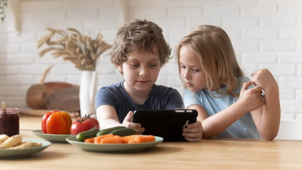 Dzieci w wieku przedszkolnym siedzące przy stole w kuchni za pomocą tabletu — Zdjęcie stockowe