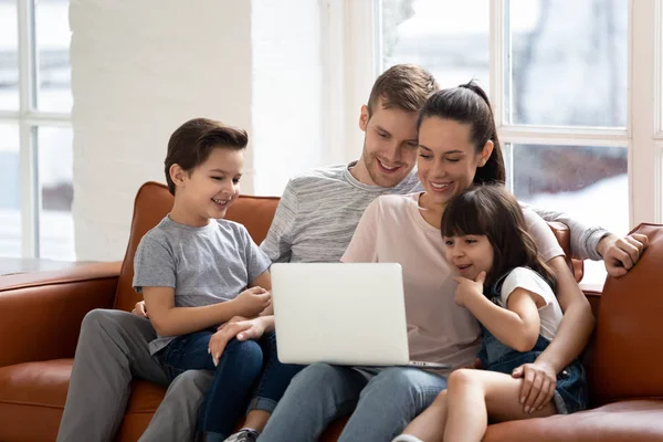 Happy parents with little daughter and son using laptop. — Stock Photo, Image