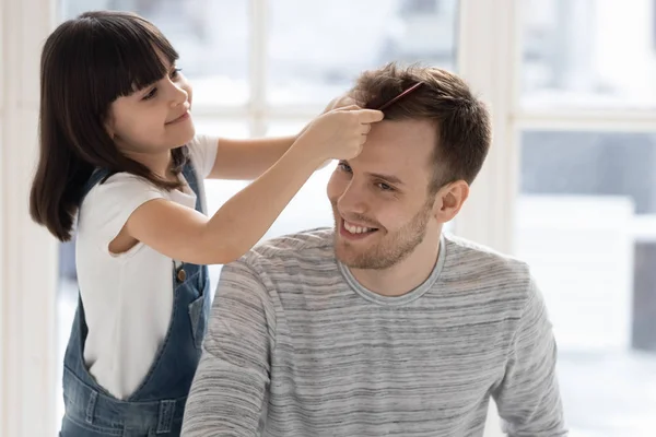Cuidado feliz preescolar hija cepillado peinado padre cabello . — Foto de Stock