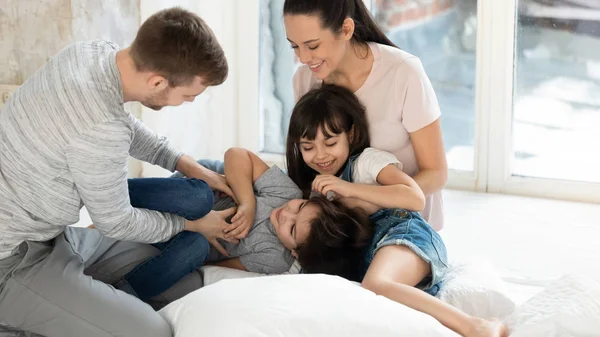 Happy family tickle children and having good time on pillows.
