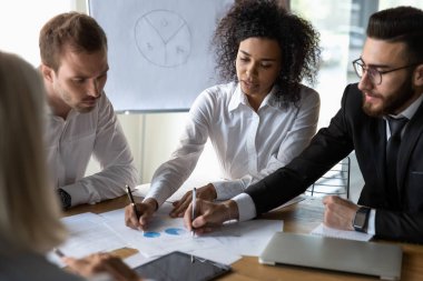 Çok ırklı meslektaşlar ofis brifinginde evrak işlerini tartıştılar