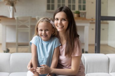 Bebek bakıcısı ve kız kanepede oturmuş kameraya bakıyorlardı.