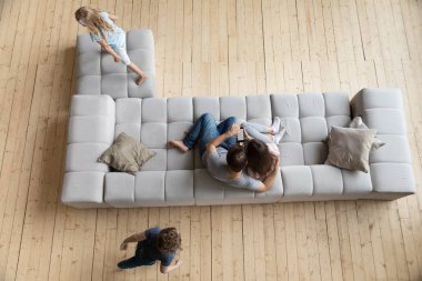 Yukarıda ebeveynler kanepede dinleniyor çocuklar oyun oynuyorlar