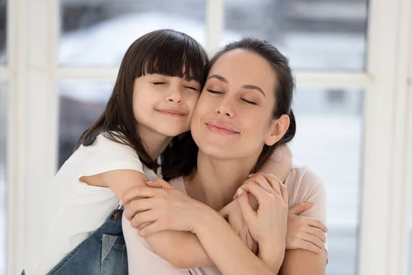 Glückliche junge Mutter und kleine süße Tochter umarmen. — Stockfoto