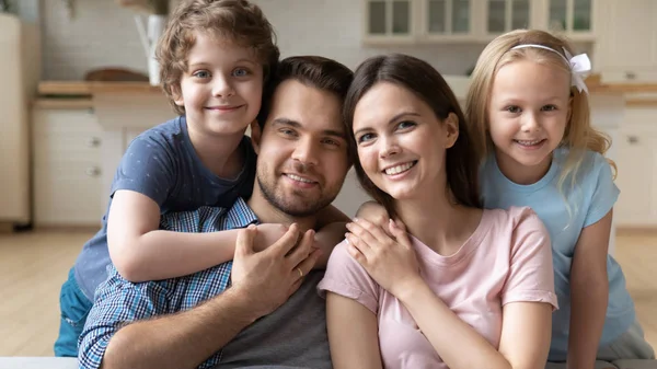 Couple souriant avec des enfants assis sur le canapé posant pour la caméra — Photo