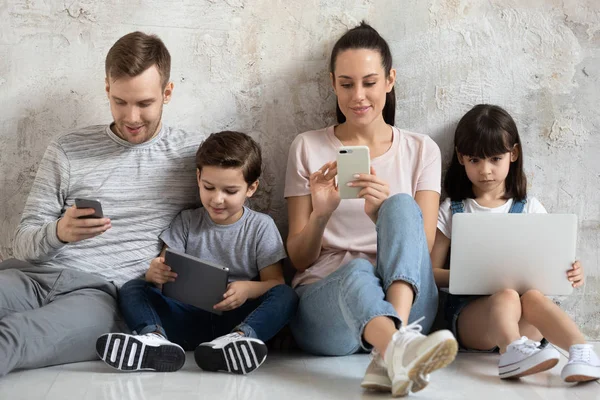 子供連れの幸せな家族は、現代的なデバイスを使用して床に座る. — ストック写真