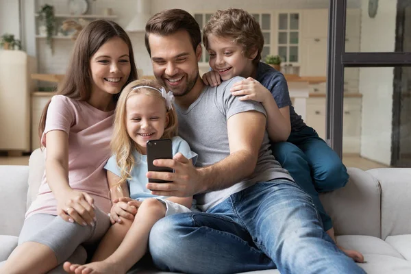 Married couple with kids play new game using smartphone — Stock Photo, Image