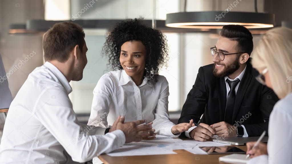 Smiling diverse colleagues discuss business ideas at team briefing