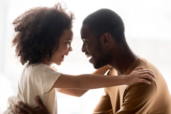 Emocionado papá negro y abrazo de hija mirando a los ojos —  Fotos de Stock