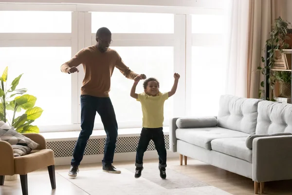 Glücklicher schwarzer Vater und Sohn haben Spaß beim gemeinsamen Springen — Stockfoto