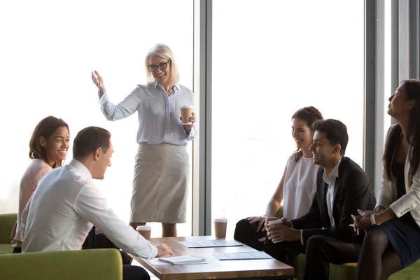 Smiling mature businesswoman holding briefing with diverse employees — Stock Photo, Image