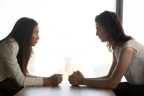 Diverse Geschäftsfrauen mit zusammengeklappten Händen sitzen einander gegenüber, Konfrontation — Stockfoto