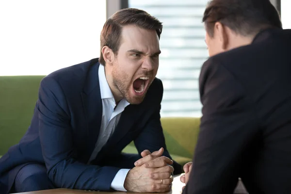 怒っている実業家が相手に叫んで、会議で侵略を示す — ストック写真
