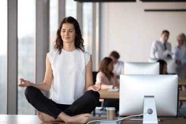 Sakin bir iş kadını, gözleri kapalı, meditasyon yapıyor.
