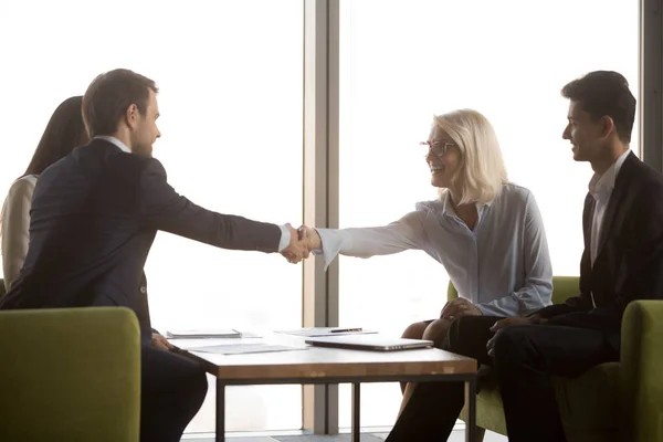 Smiling mature businesswoman shaking hand of business partner at meeting — Stock Photo, Image