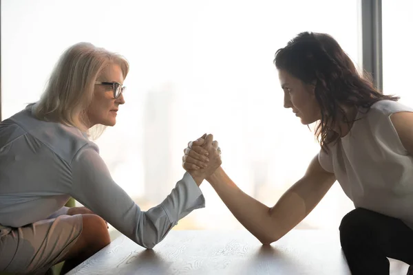 Side view mature and young businesswomen arm wrestling, confrontation — Stock Photo, Image