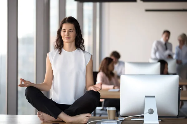 Calm businesswoman with closed eyes meditating on office desk — Stock Photo, Image