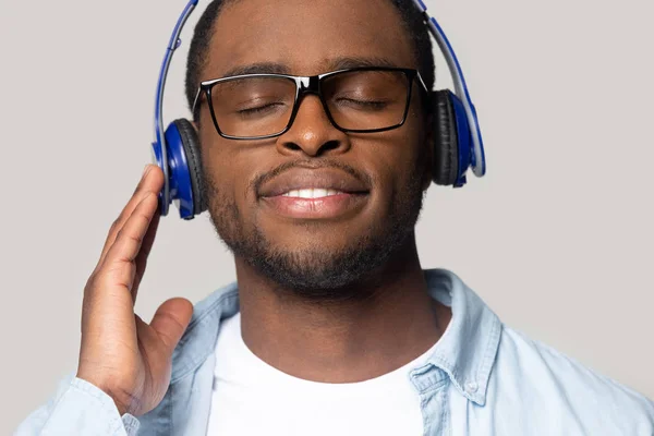 Glimlachende jonge Afro-Amerikaanse man genieten van favoriete muziek tracks. — Stockfoto