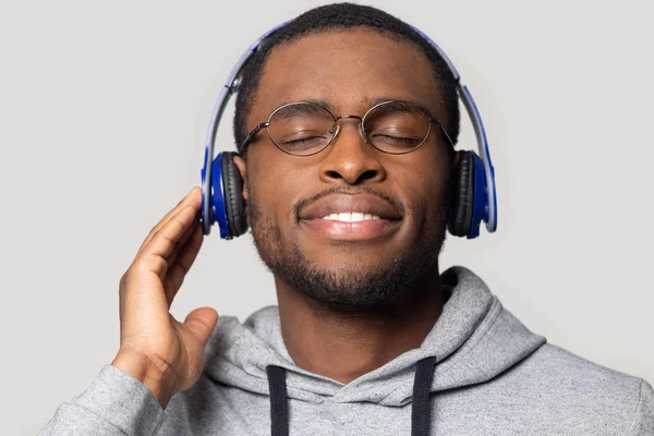 Satisfeito homem americano africano milenar usando fones de ouvido sem fio modernos . — Fotografia de Stock