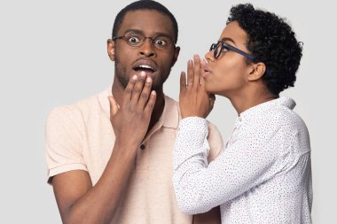 Young african american woman in eyeglasses whispering secret to husband. clipart