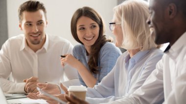 Gülümseyen çeşitli çalışanlar kahve molasında konuşarak eğleniyor.