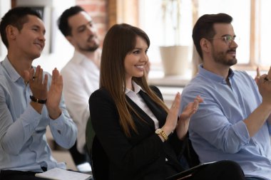 Çeşitli iş adamları sırada oturup başarılı bir semineri alkışlıyorlar.