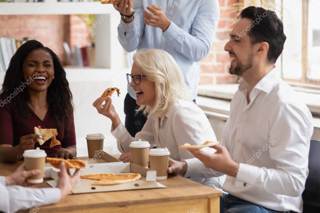 Multi racial colleagues eat pizza enjoy break during working day