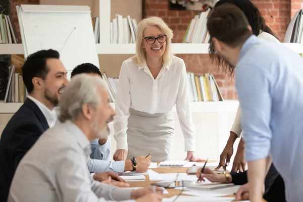 Mujer de negocios envejecida positiva y diversos colegas en la reunión de oficina — Foto de Stock