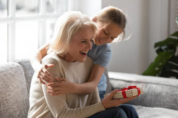 Liefdevolle meisje knuffel groet opgewonden grootmoeder met verjaardag — Stockfoto