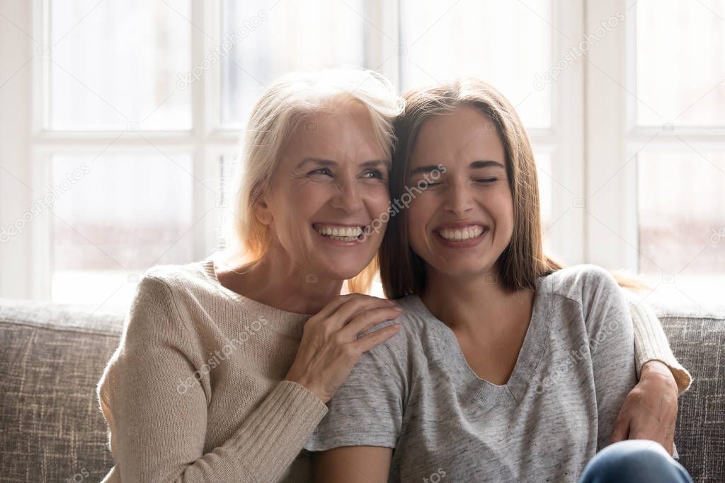 Happy senior mom and adult daughter have fun at home