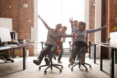 Çeşitli çalışanlar ofis sandalyelerinde gülerek eğleniyor.