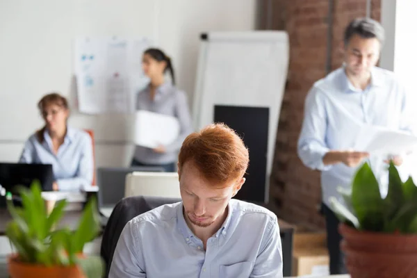 I dipendenti che lavorano in ufficio condiviso si concentrano sull'uomo rosso occupato — Foto Stock