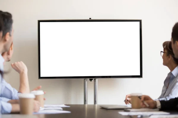 Businesspeople sitting in boardroom looking at tv with white blank — Stock Photo, Image